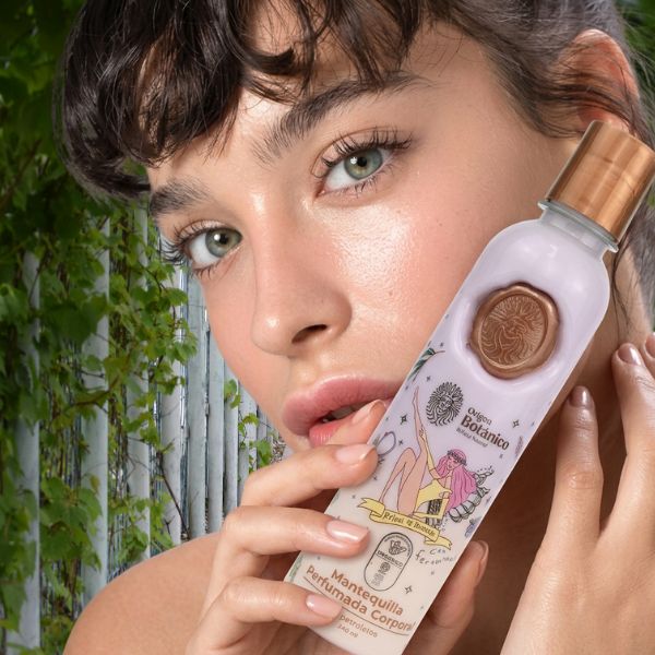 Mujer de ojos verdes mosntrando con sus manos al lado del rostro la mantequilla de ritual botanico 