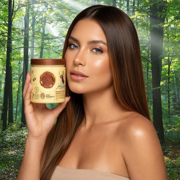 mujer con pelo castaño y ojos azules mostrando a la do de su rostro un pote o tarro de una mascarilla reparadora